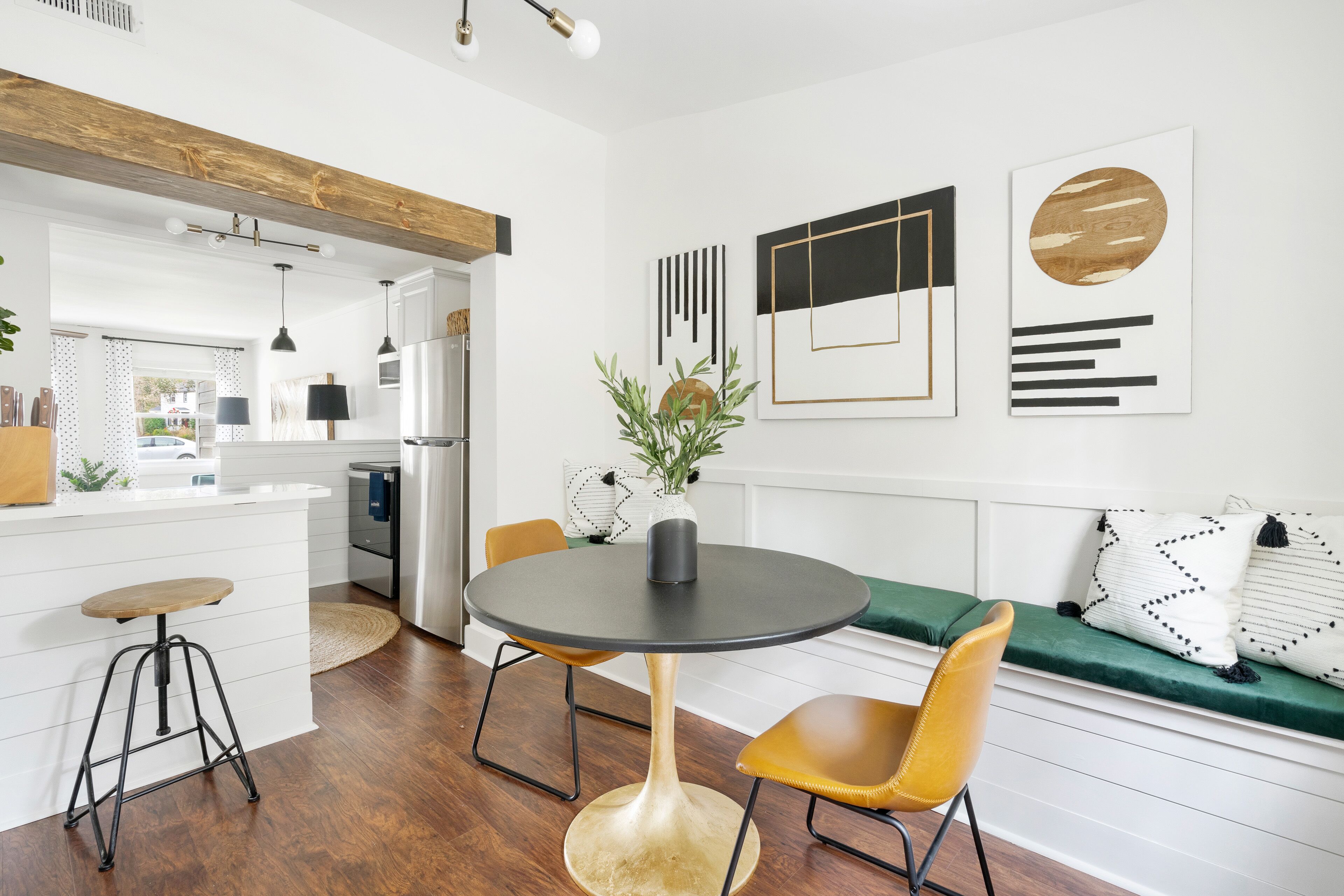 Une cuisine moderne avec des meubles blancs, un plafond en bois et un coin repas comprenant une table ronde et des chaises.