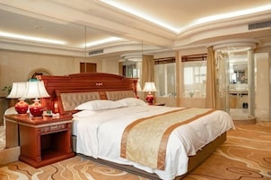 Um quarto de hotel espaçoso com uma cama grande, abajures, mesa de cabeceira e um espelho.