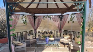 A covered patio area with wicker furniture, a glass table, and a potted plant. - Authentic 100 year old barn, indoor pool (Gouttières)