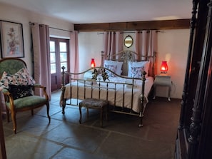 A traditional bedroom with a four-poster bed, a chair with floral upholstery, and a bedside table with a red lamp. - Authentic 100 year old barn, indoor pool (Gouttières)