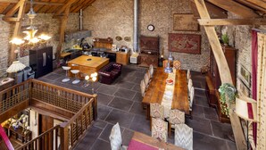 A rustic dining area with a long wooden table and chairs, a stone wall, and a wooden ceiling. - Authentic 100 year old barn, indoor pool (Gouttières)