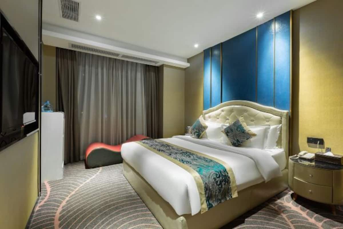 Une chambre d’hôtel avec un grand lit, une table de chevet, un bureau et une chaise.