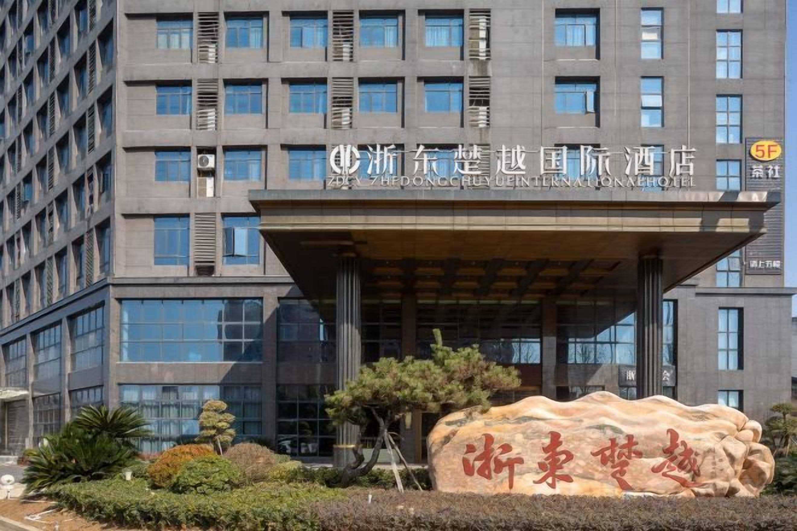 A hotel entrance with a large rock sculpture and a sign with Chinese characters.