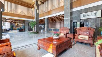 A spacious lobby with high ceilings, wooden paneling, and a large reception desk.