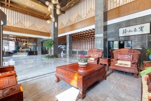 A spacious lobby with high ceilings, wooden paneling, and a large reception desk.