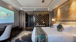 Ein modernes Hotelzimmer mit einem großen Bett, einem Schreibtisch und einem Bildschirm, der Zimmerauswahlmöglichkeiten zeigt.