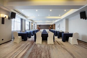 A conference room with a long table and chairs, large windows, and ceiling lights.