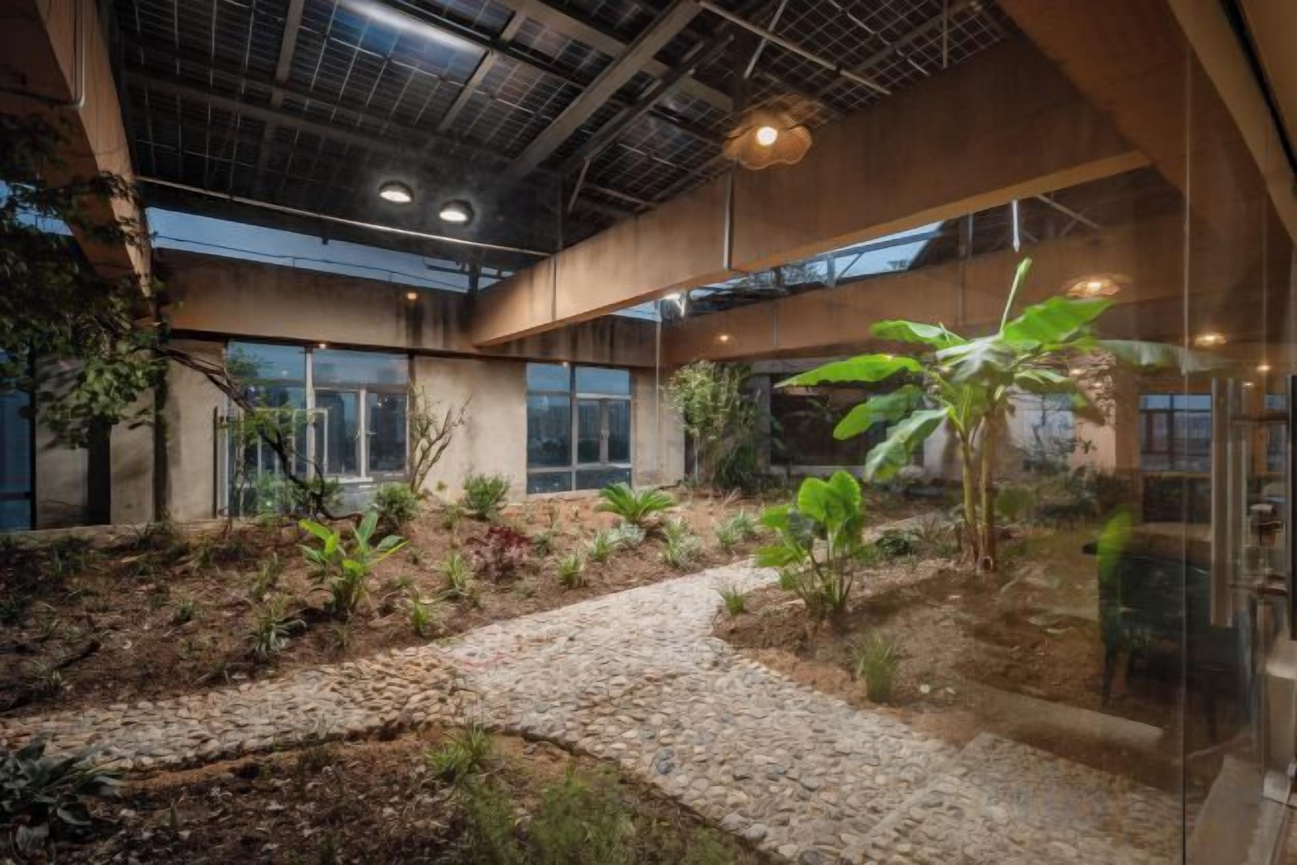Un jardín interior con un sendero de piedra, ventanas grandes y plantas colgantes.