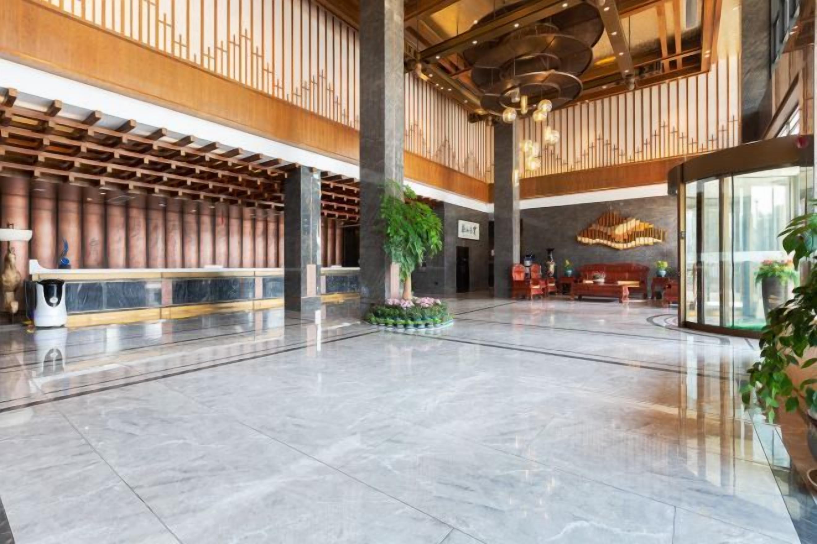 A spacious lobby with a high ceiling, a reception desk, and a large chandelier.