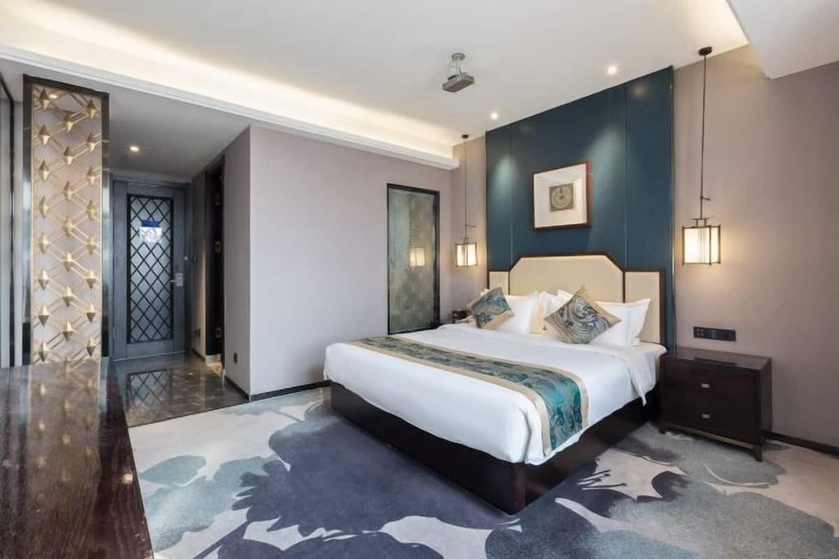 Une chambre à coucher moderne avec un grand lit, une table de chevet et un luminaire fixé au mur.