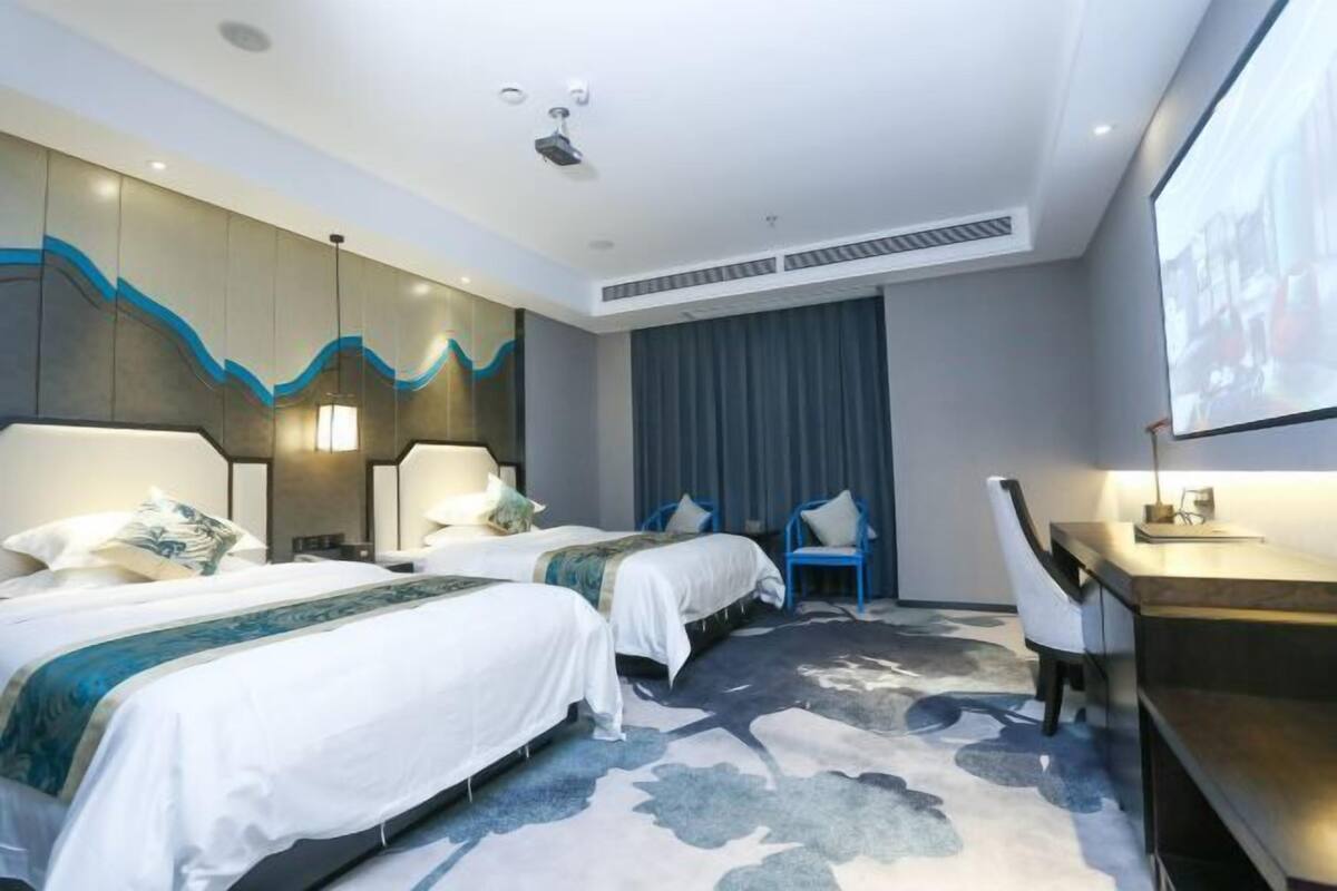 Une chambre d’hôtel avec deux lits, un bureau et une chaise.