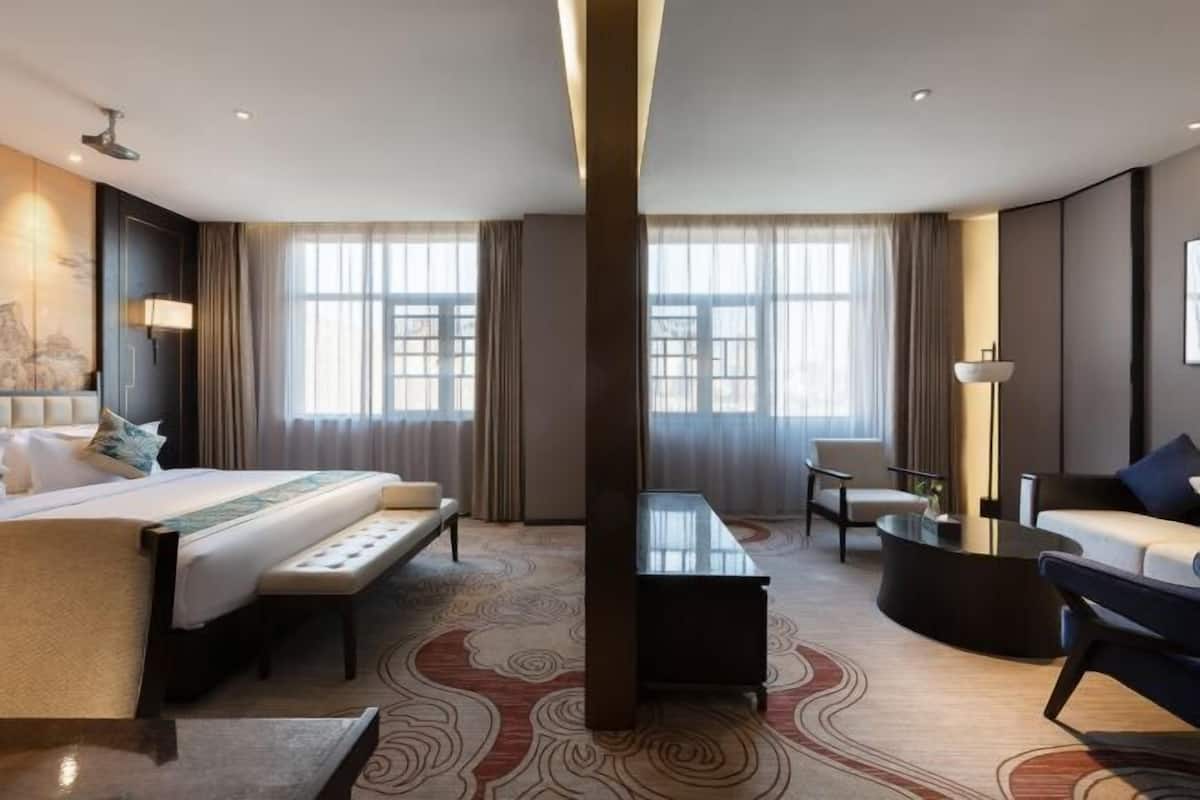 Une chambre d’hôtel avec un grand lit, un bureau, une chaise et un canapé.