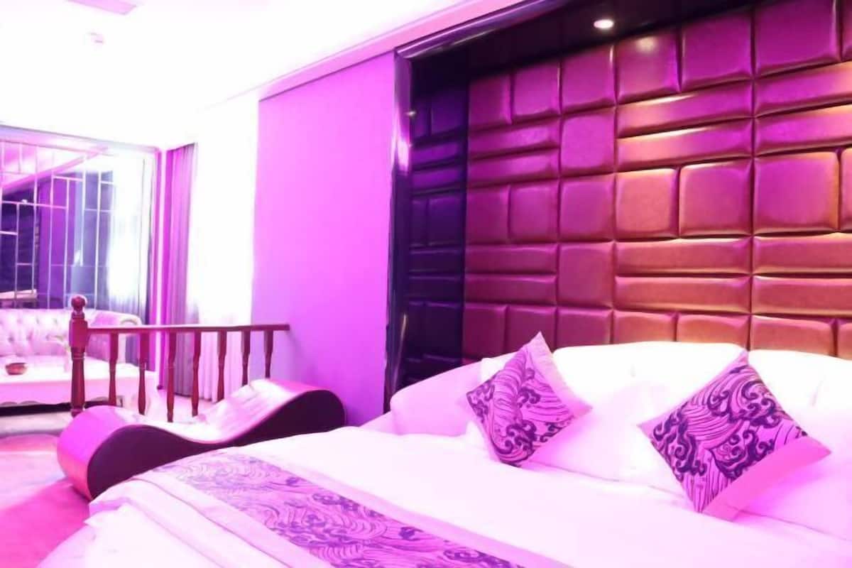 A bedroom with a large bed, a headboard, and a window.