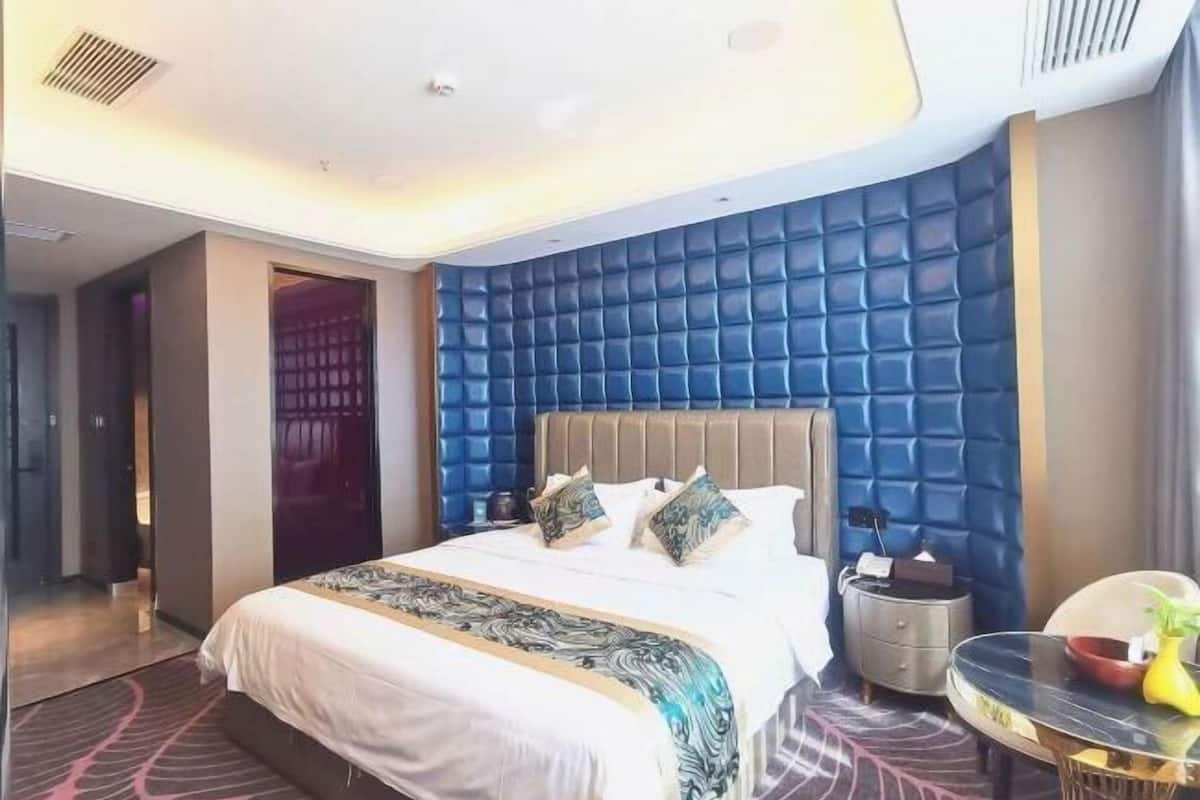 Une chambre d’hôtel moderne avec un grand lit, une table ronde et un mur d’accent bleu.