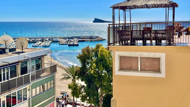 Blick auf die Küste mit Strand, einer Pier und einem Gebäude mit Strohdach.