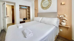 Ein Hotelzimmer mit einem Bett, einem Deckenventilator, einem Holzschrank, einem Spiegel und einer Vase mit Blumen.