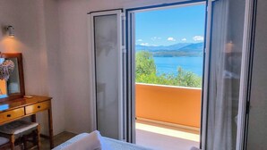 Un dormitorio con cama, escritorio y vistas a un lago y montañas.