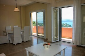 Une pièce spacieuse avec un balcon, un coin repas doté de meubles blancs et une table agrémentée d’un vase décoratif.