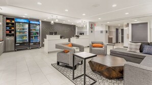 A modern hotel lobby with seating areas, a reception desk, and two beverage dispensers. -  Best Western Plus Cleveland Inn & Suites (Cleveland)
