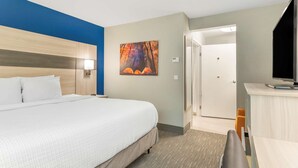 A hotel room with a large bed, a desk, a chair, and a painting on the wall. -  Best Western Plus Cleveland Inn & Suites (Cleveland)