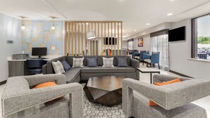 A modern living room with a sectional sofa, a coffee table, and grey upholstered chairs. -  Best Western Plus Cleveland Inn & Suites (Cleveland)