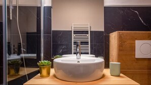 Un baño moderno con un lavamanos redondo, un perchero y un armario de madera.
