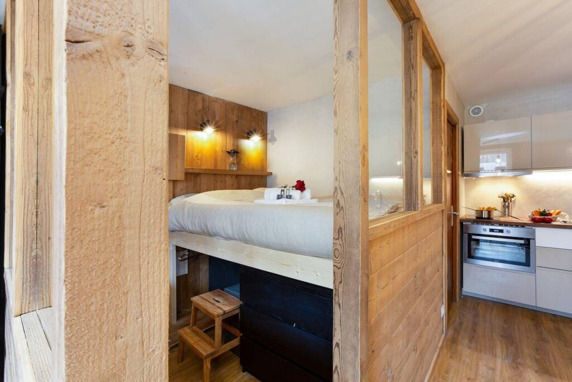 Ein kleines Schlafzimmer mit Etagenbett, Holzwänden und einer kleinen Küchenzeile mit Herd und Backofen.