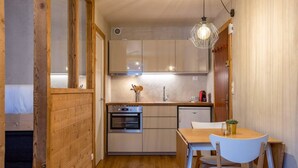 Una cocina compacta con armarios de madera, horno empotrado, lavamanos y comedor con mesa y sillas.
