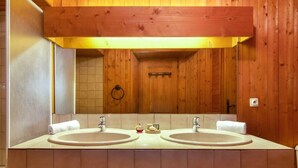 A wooden cabin-style bathroom with two sinks, a mirror, and a towel rack.
