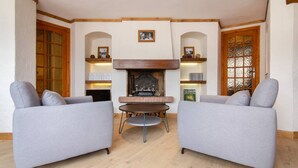 A living room with two grey sofas, a central round table, and a fireplace.