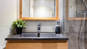 A bathroom with a wooden vanity, a sink, a mirror, and a potted plant.