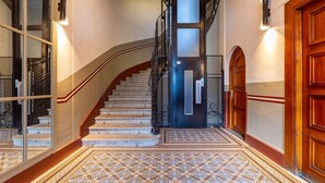 A grand staircase with a black metal railing, a wooden door, and a patterned floor. - Montcler - Moderne&Spacieux 3CH Apart Hypercentre | Vue 180° (Chamonix-Mont-Blanc)