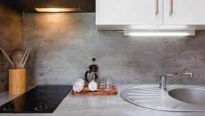 Une cuisine moderne dotée d’une plaque de cuisson à induction noire, d’un moulin à café et d’un évier avec un robinet au design original.