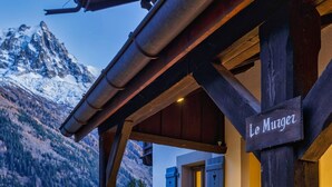 Un bâtiment en bois avec une enseigne indiquant « Le Murger » et une vue sur les montagnes en arrière-plan.