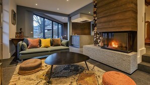 Un salon moderne avec une cheminée, un canapé avec des coussins, une table basse et un tapis.