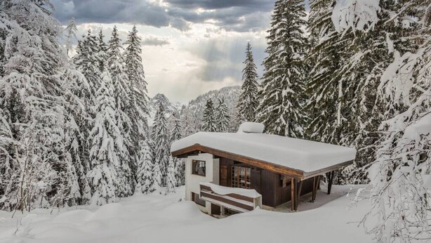 Un chalet moderne entouré d’arbres couverts de neige.