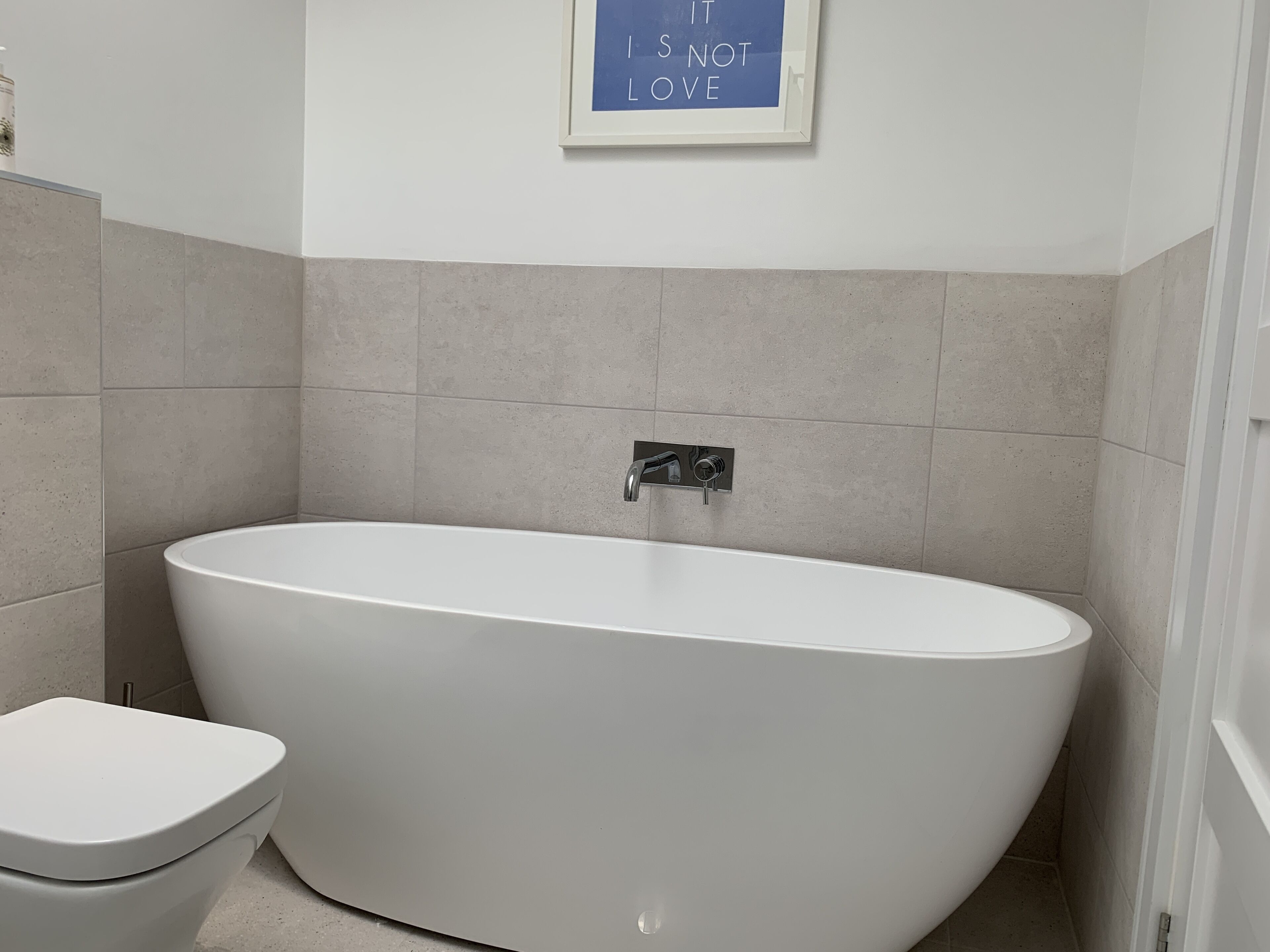 A modern bathroom with a freestanding bathtub, a toilet, and a wall-mounted sink.