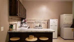 Una cocina con encimera de mármol, taburetes de madera, estufa y refrigerador.