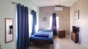 Un dormitorio con cama, cómoda, televisor y puerta que da a otra habitación.