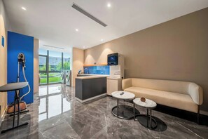 A modern hotel lobby with a seating area, a washing station, and a large window offering a view of the outdoors.
