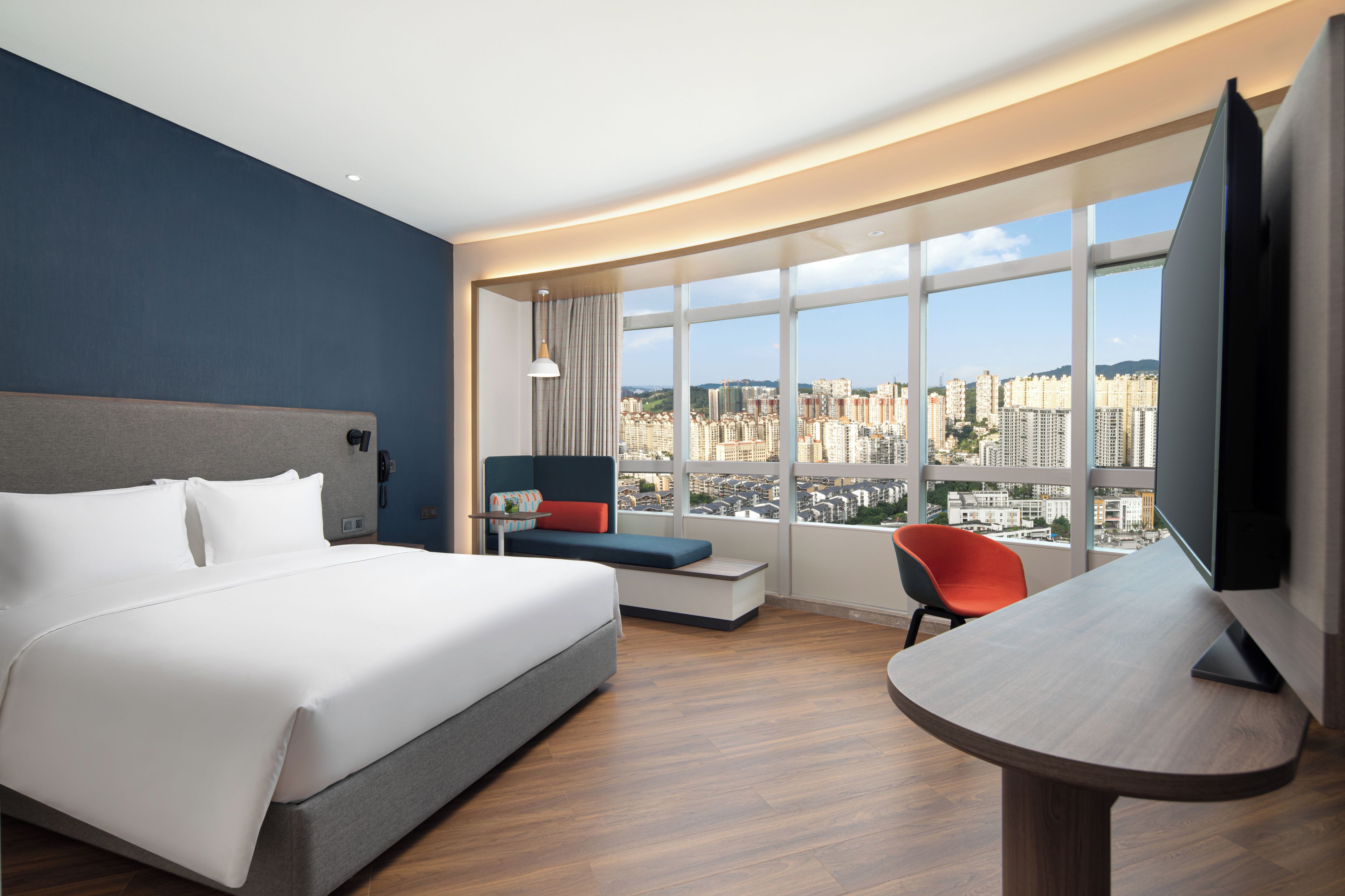 A hotel room with a large bed, a seating area with a view, and a television.