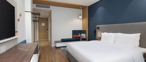 A modern hotel room with a large bed, a desk, and a television.
