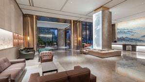 A spacious lobby with leather sofas, a reception desk, and a large decorative wall. - Ramada by Wyndham Huangshi Huangshigang (Huangshi)