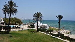 Une station balnéaire dotée de palmiers, d’une piscine et d’une plage.