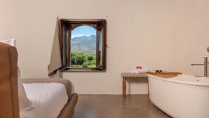Ein Schlafzimmer mit Bett, Fenster mit Bergblick, Badezimmer mit Badewanne und Waschbecken.