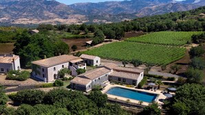 Eine Villa mit Swimmingpool, umgeben von Weinbergen und Bergen.