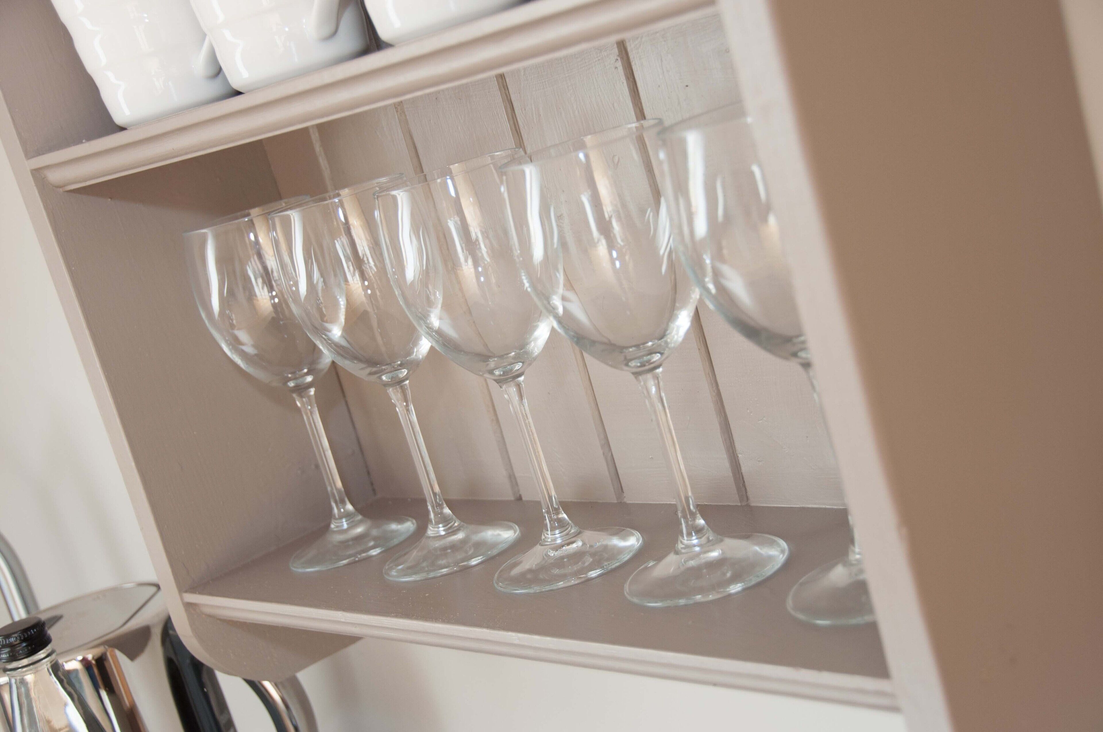 A shelf with several clear wine glasses.