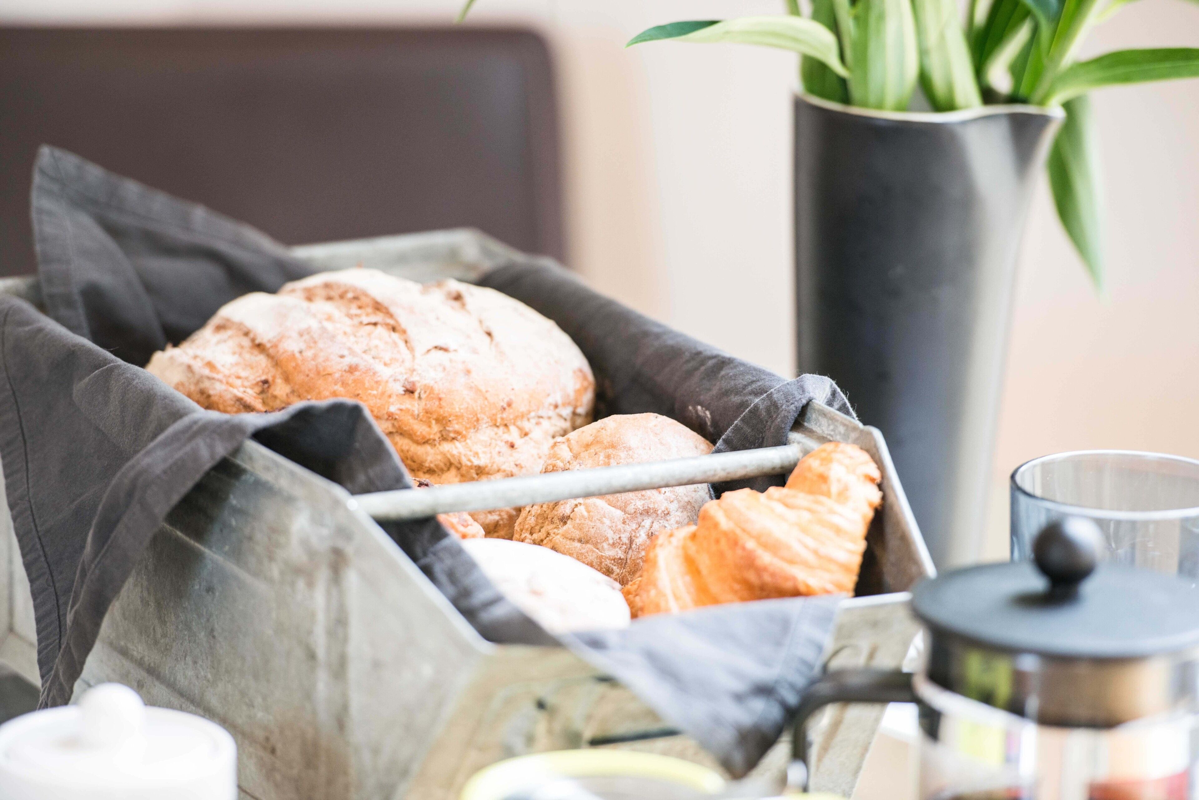 A basket of bread and a coffee pot.