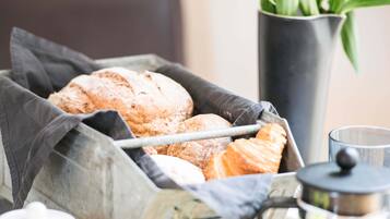 A basket of bread and a coffee pot.