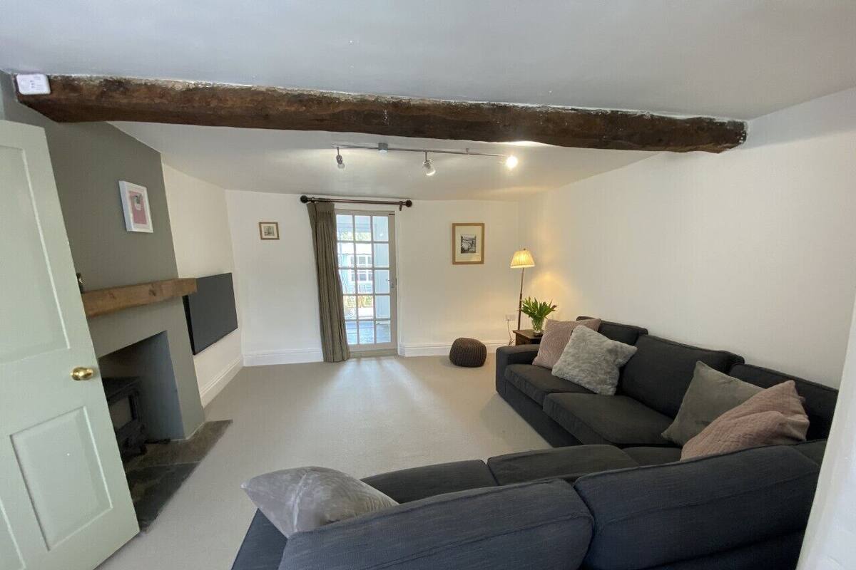 A cozy living room with a grey sofa, a fireplace, and a door leading to another room.
